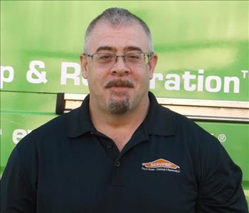 Male SERVPRO employee standing in front of a SERVPRO vehicle. 
