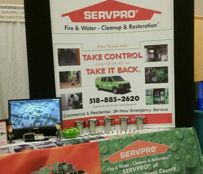 Table with SERVPRO banner on front and large sign sitting on it