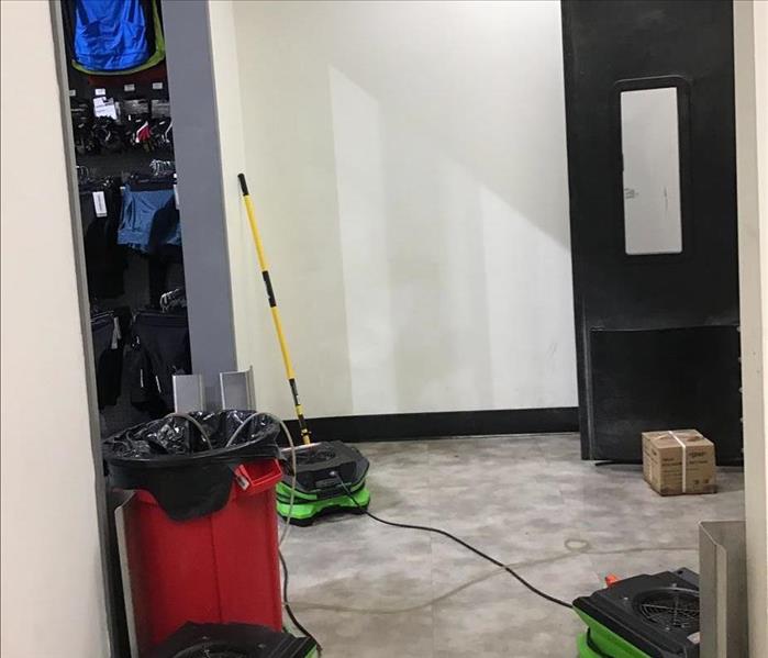SERVPRO air movers operating in a hallway with a drainage bin